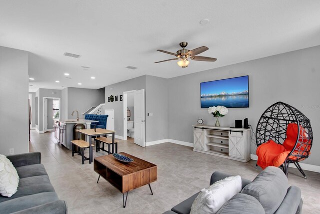 living room with ceiling fan, sink, and light tile patterned floors