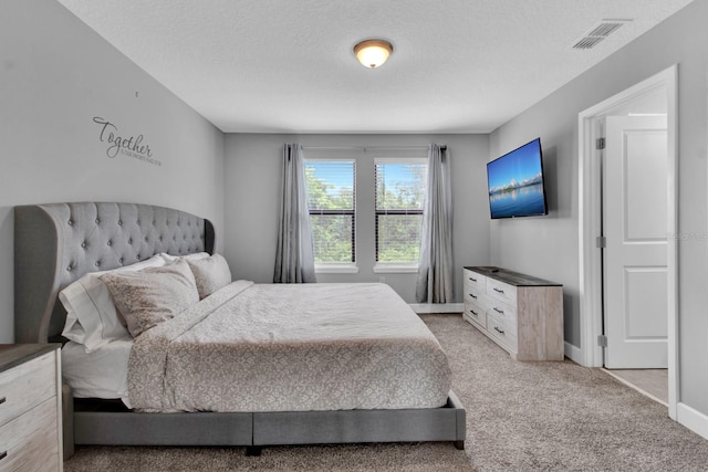 bedroom featuring a textured ceiling and light colored carpet