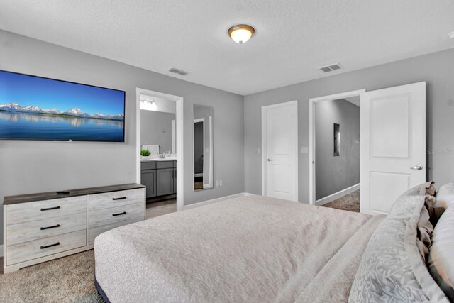 bedroom featuring a textured ceiling, connected bathroom, and carpet flooring