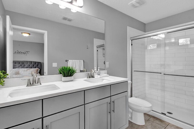 bathroom with tile patterned floors, toilet, an enclosed shower, and vanity