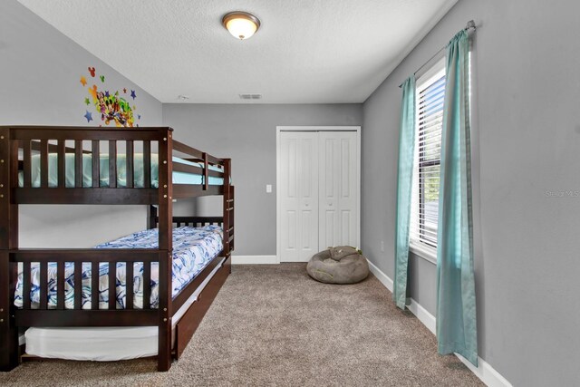 carpeted bedroom with a closet and a textured ceiling