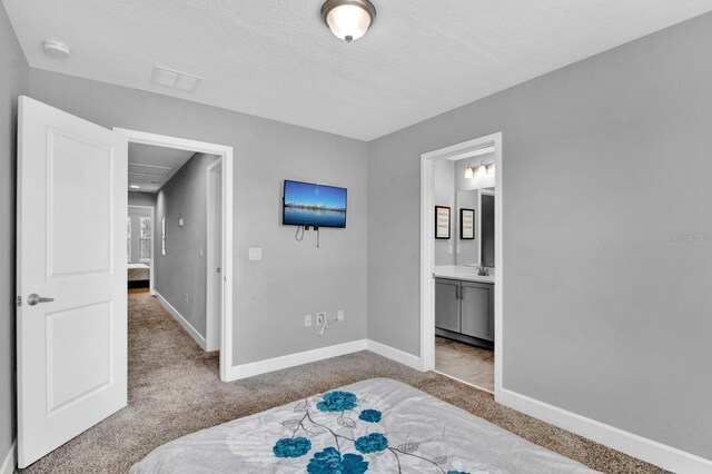 carpeted bedroom featuring ensuite bath, a textured ceiling, and sink