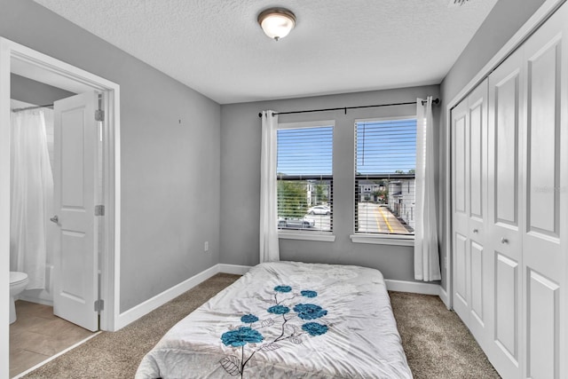 bedroom featuring a textured ceiling, ensuite bathroom, and tile patterned flooring