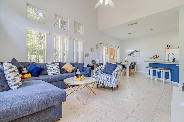 living room featuring a high ceiling, light tile patterned floors, and ceiling fan