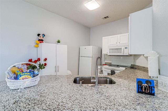 kitchen featuring a textured ceiling, light stone countertops, white appliances, sink, and decorative backsplash