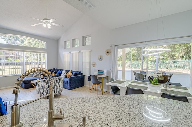 living room featuring a textured ceiling, high vaulted ceiling, light tile patterned flooring, and ceiling fan