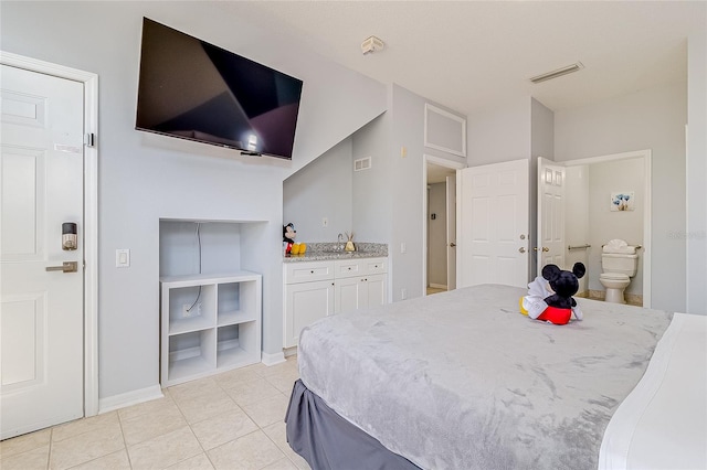 bedroom with ensuite bath and light tile patterned floors