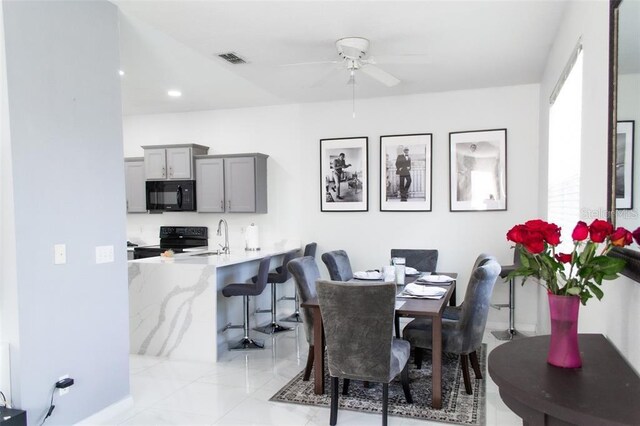 dining area with ceiling fan, sink, and light tile patterned flooring