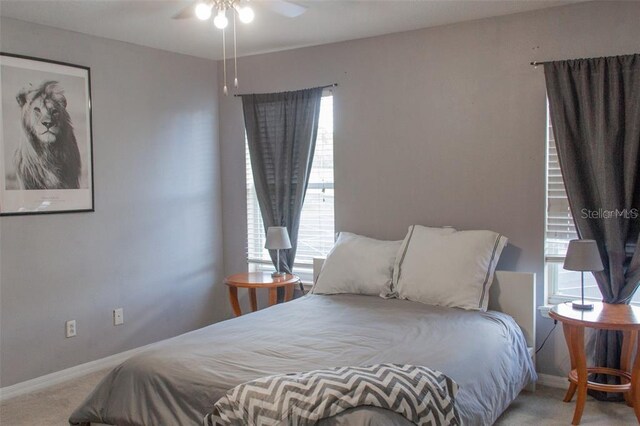 carpeted bedroom featuring ceiling fan and multiple windows