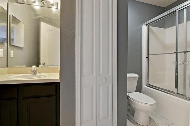 full bathroom with tile patterned floors, enclosed tub / shower combo, toilet, and vanity