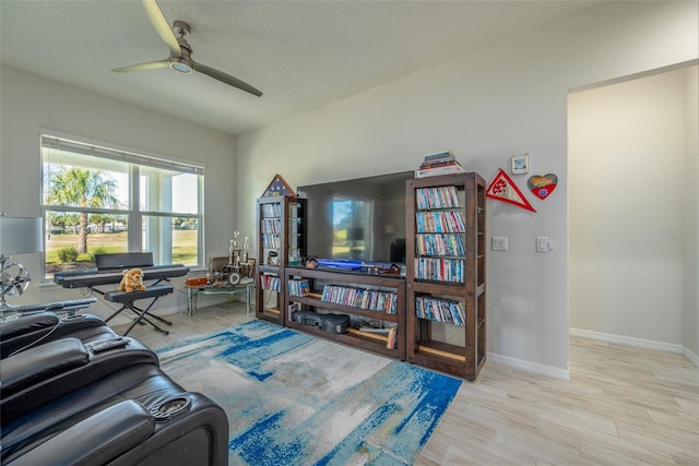 living room with a textured ceiling, ceiling fan, and light hardwood / wood-style floors