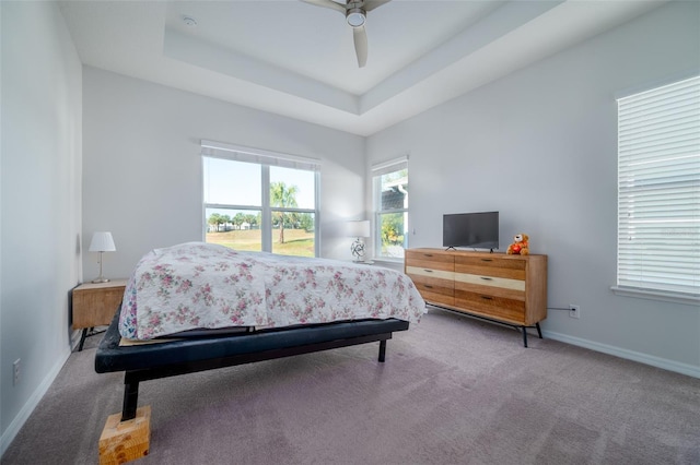 bedroom with a raised ceiling, ceiling fan, and carpet flooring