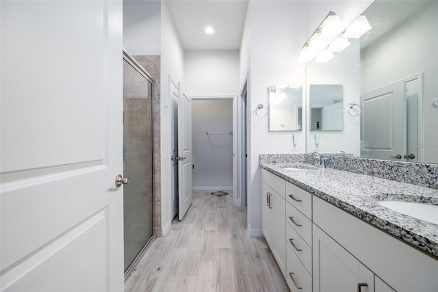 bathroom featuring wood-type flooring, a shower with door, and vanity