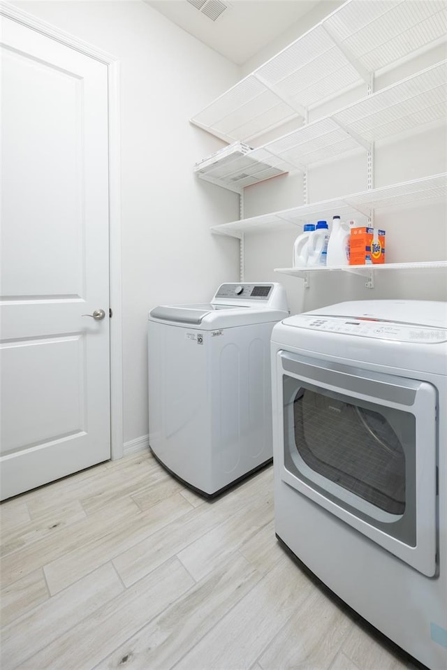 clothes washing area featuring light hardwood / wood-style flooring and independent washer and dryer