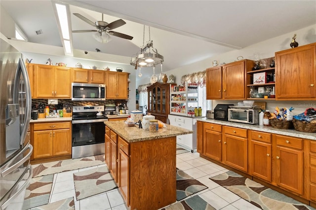 kitchen with light tile patterned floors, a center island, stainless steel appliances, and ceiling fan