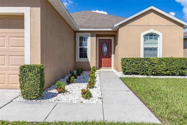 doorway to property featuring stucco siding, an attached garage, and roof with shingles