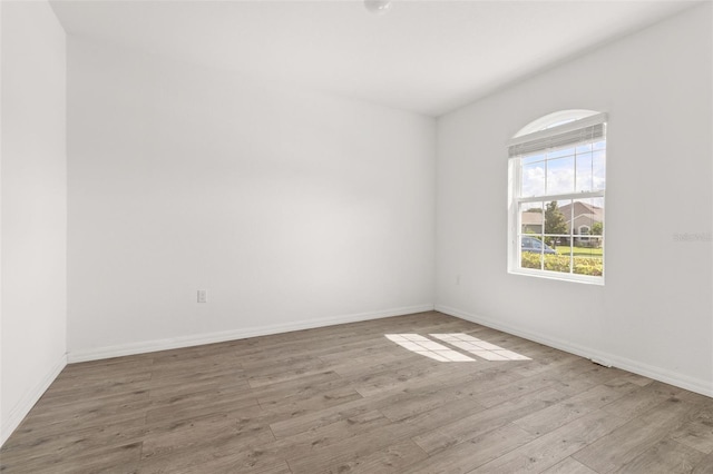 spare room featuring baseboards and wood finished floors