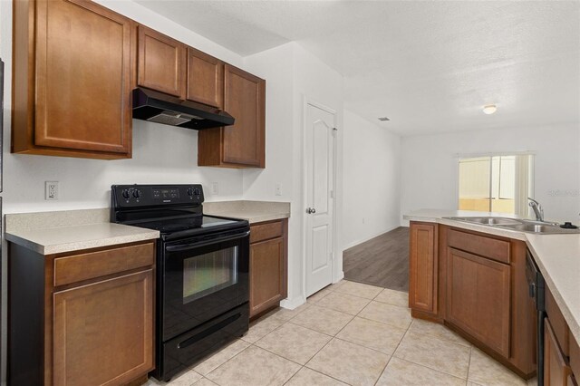 kitchen featuring light tile patterned floors, a textured ceiling, black electric range oven, and sink