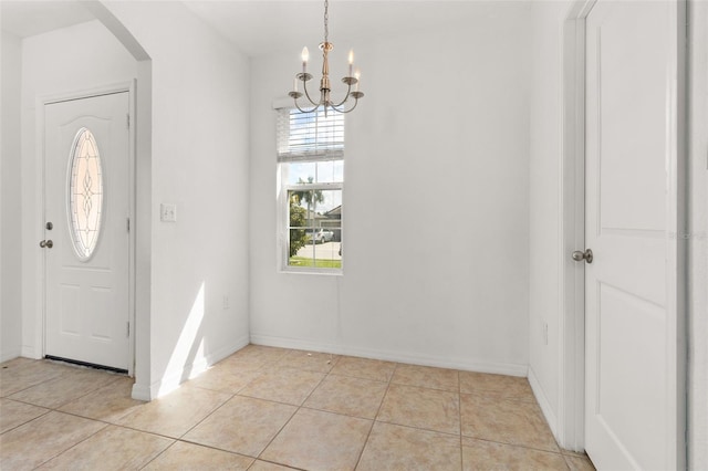 foyer with a notable chandelier, light tile patterned floors, baseboards, and arched walkways