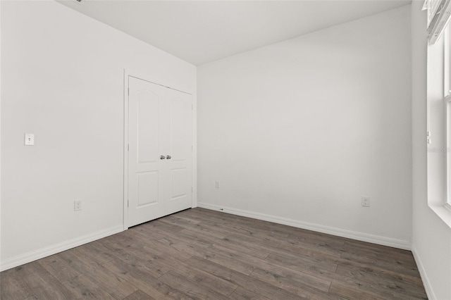 unfurnished room featuring baseboards and dark wood finished floors