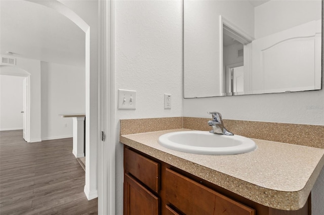 bathroom with vanity, wood finished floors, visible vents, and baseboards