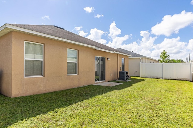 back of property featuring a yard, central AC unit, fence, and stucco siding