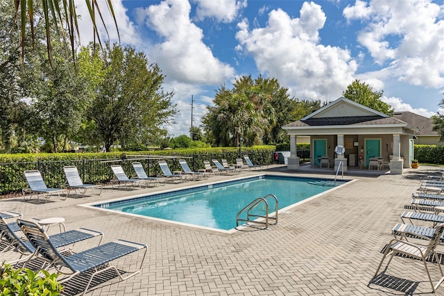 community pool with a patio area and fence