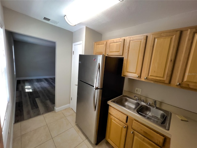 kitchen featuring light wood-type flooring, stainless steel fridge, light brown cabinets, and sink