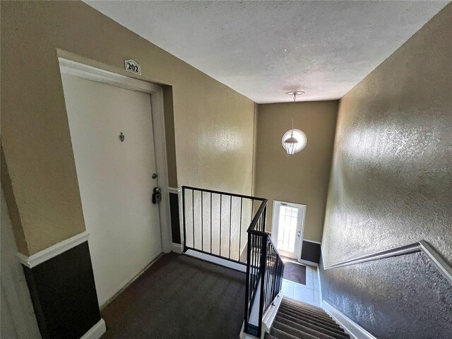 stairway with a textured ceiling and carpet