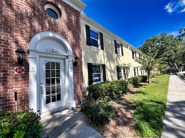 doorway to property featuring brick siding and stucco siding