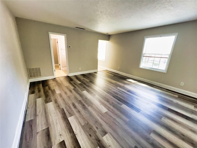 unfurnished room with a textured ceiling and wood-type flooring