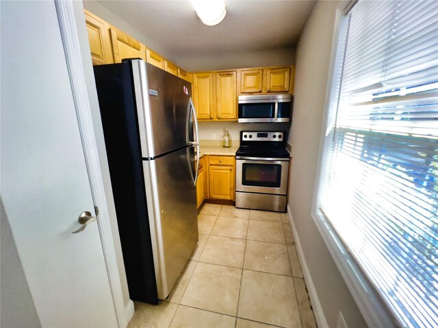 kitchen featuring light brown cabinetry, light tile patterned floors, and appliances with stainless steel finishes