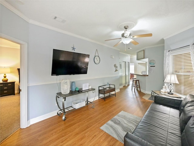 living room featuring ornamental molding, light hardwood / wood-style flooring, and ceiling fan