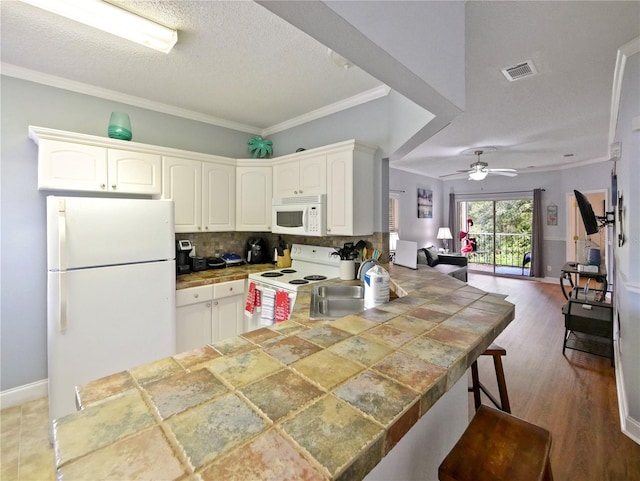 kitchen with white appliances, dark hardwood / wood-style flooring, kitchen peninsula, sink, and ceiling fan