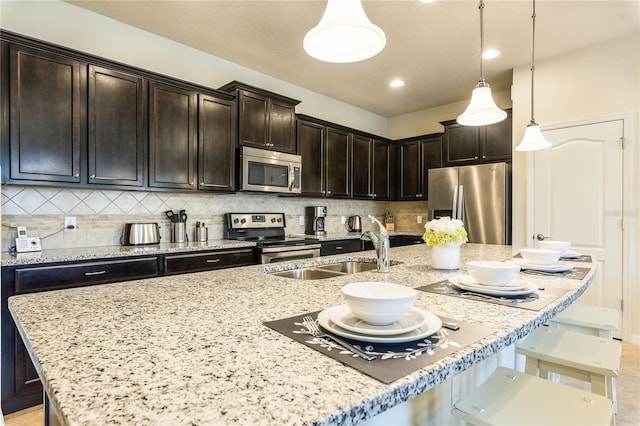 kitchen featuring stainless steel appliances, light stone counters, decorative light fixtures, and backsplash