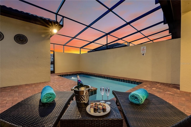 pool at dusk featuring a lanai and a patio area