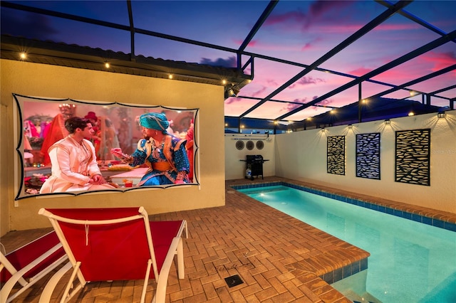 pool at dusk featuring a lanai and a patio