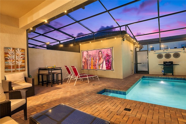 pool at dusk featuring glass enclosure and a patio area