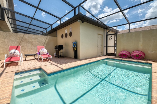 view of pool with glass enclosure, a patio, and area for grilling