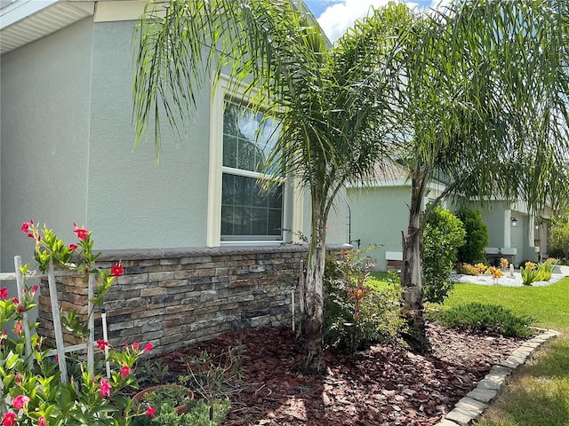 view of property exterior with stone siding, a lawn, and stucco siding