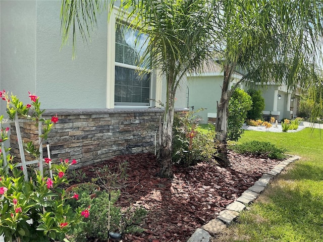 view of home's exterior with stone siding, a yard, and stucco siding