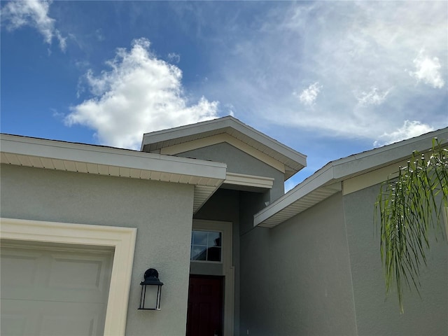 entrance to property with an attached garage and stucco siding