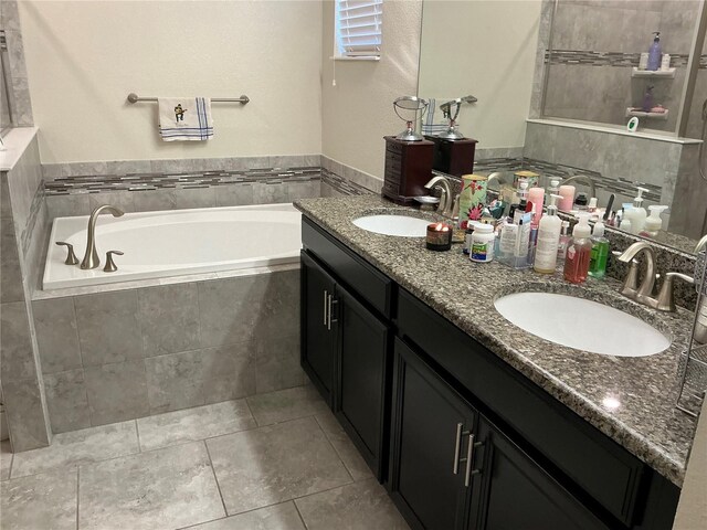 bathroom featuring tile patterned flooring, vanity, and tiled tub