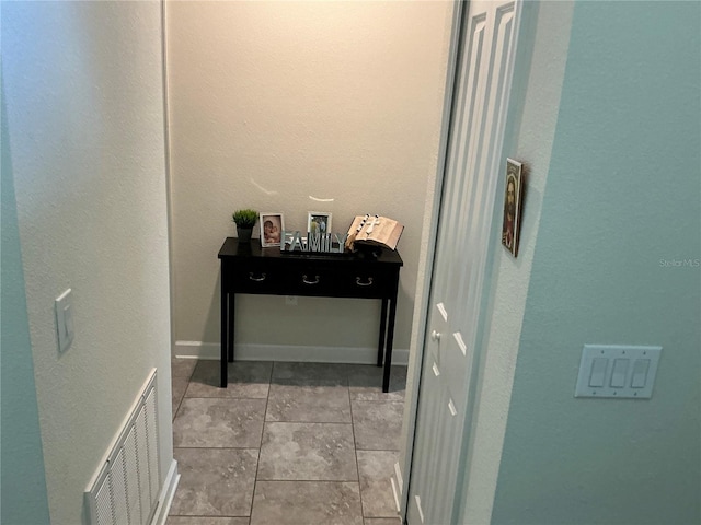 corridor featuring light tile patterned floors, baseboards, and visible vents