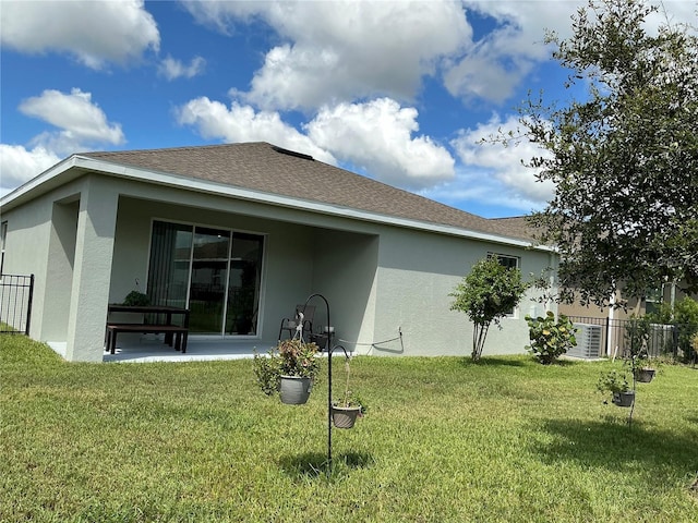 back of property with a patio area, a lawn, fence, and stucco siding