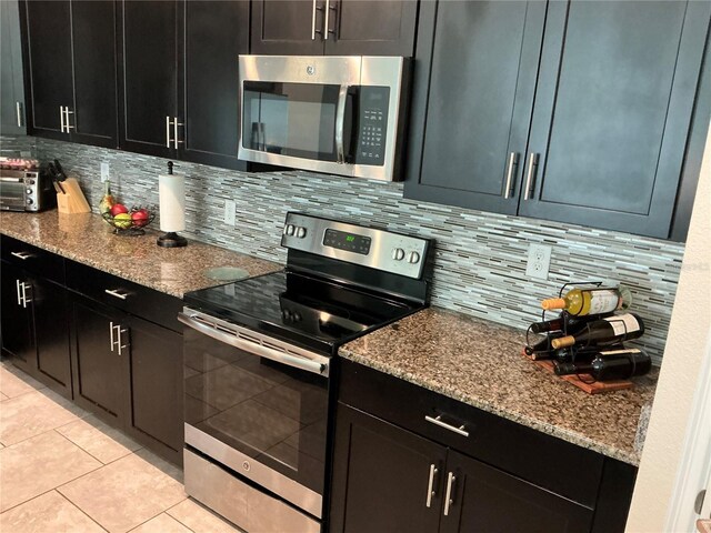 4183 Cortland Dr, Davenport, FL 33837 - kitchen featuring light tile patterned floors, appliances with stainless steel finishes, decorative backsplash, and light stone countertops