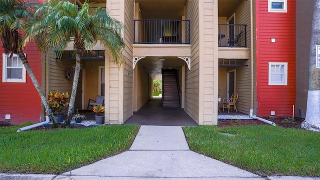 entrance to property featuring a balcony and a yard