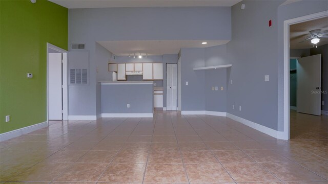 unfurnished living room featuring light tile patterned floors, visible vents, a ceiling fan, and baseboards