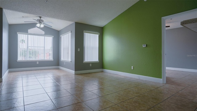 empty room with lofted ceiling, ceiling fan, light tile patterned flooring, and a textured ceiling