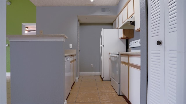 kitchen with a textured ceiling, light tile patterned floors, white appliances, and white cabinetry